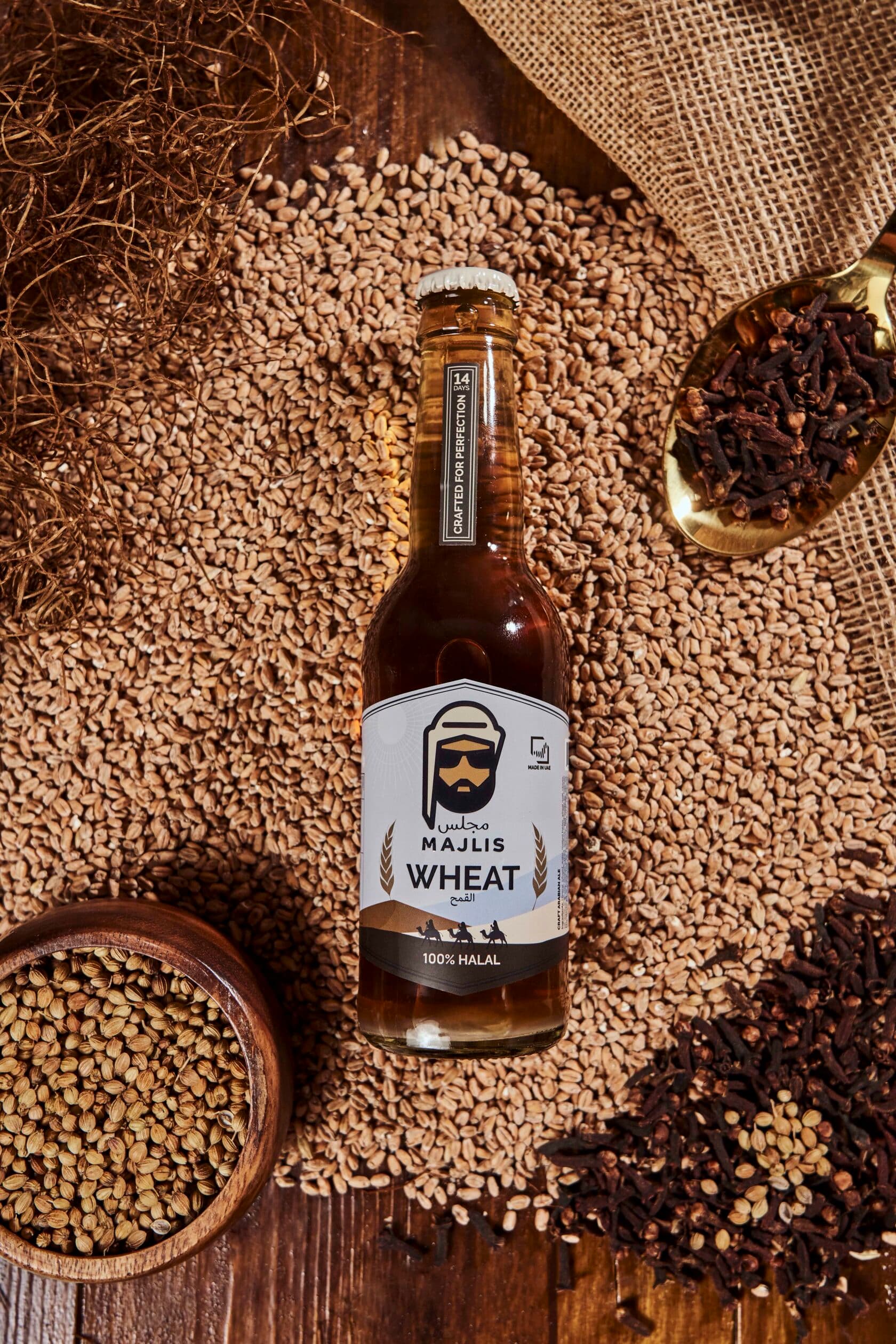 Majlis Wheat non-alcoholic craft Arabian ale bottle on barley with cloves and burlap